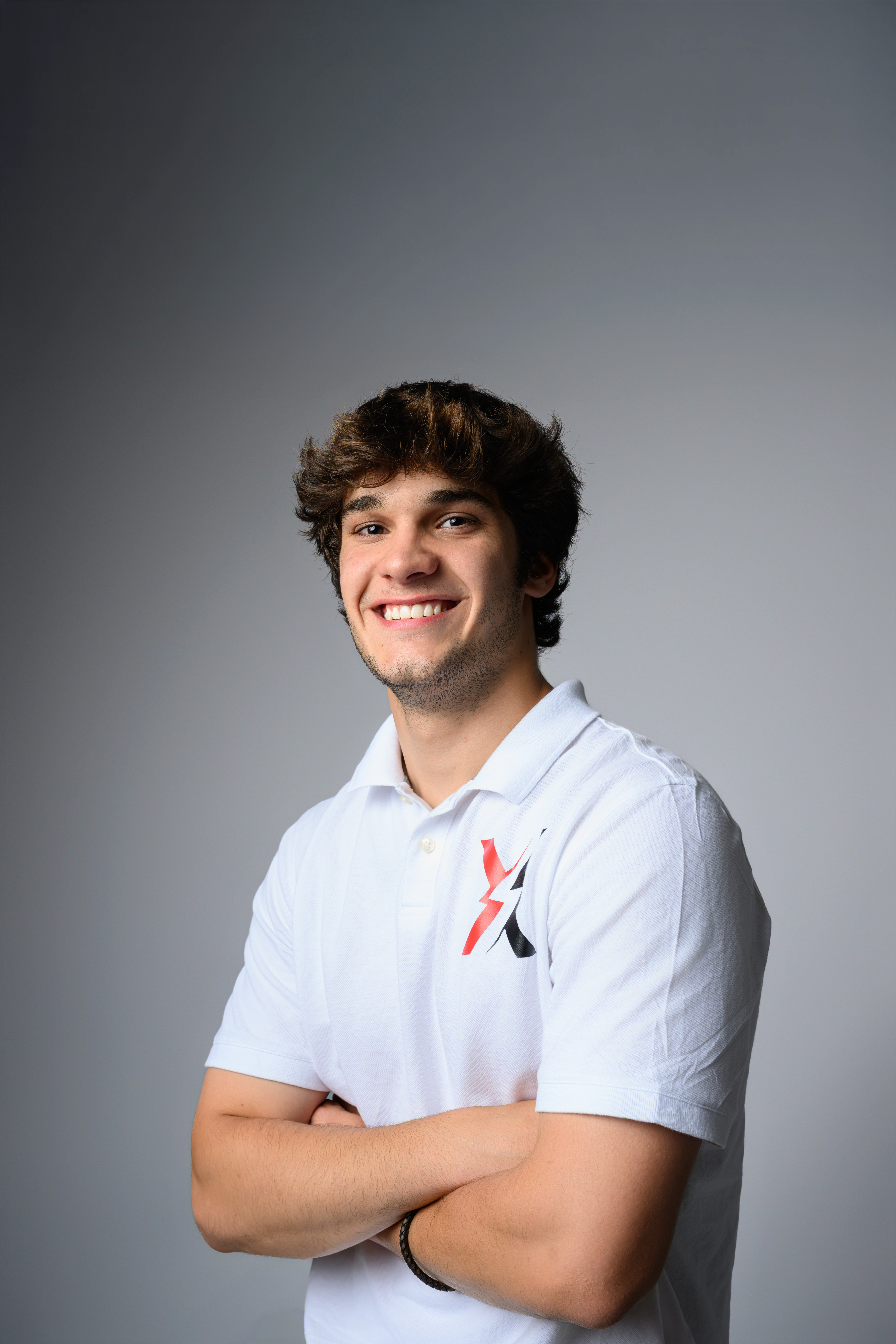 Jace Bauer, goalie coach at X Factor Lacrosse, standing in training gear and smiling for a headshot